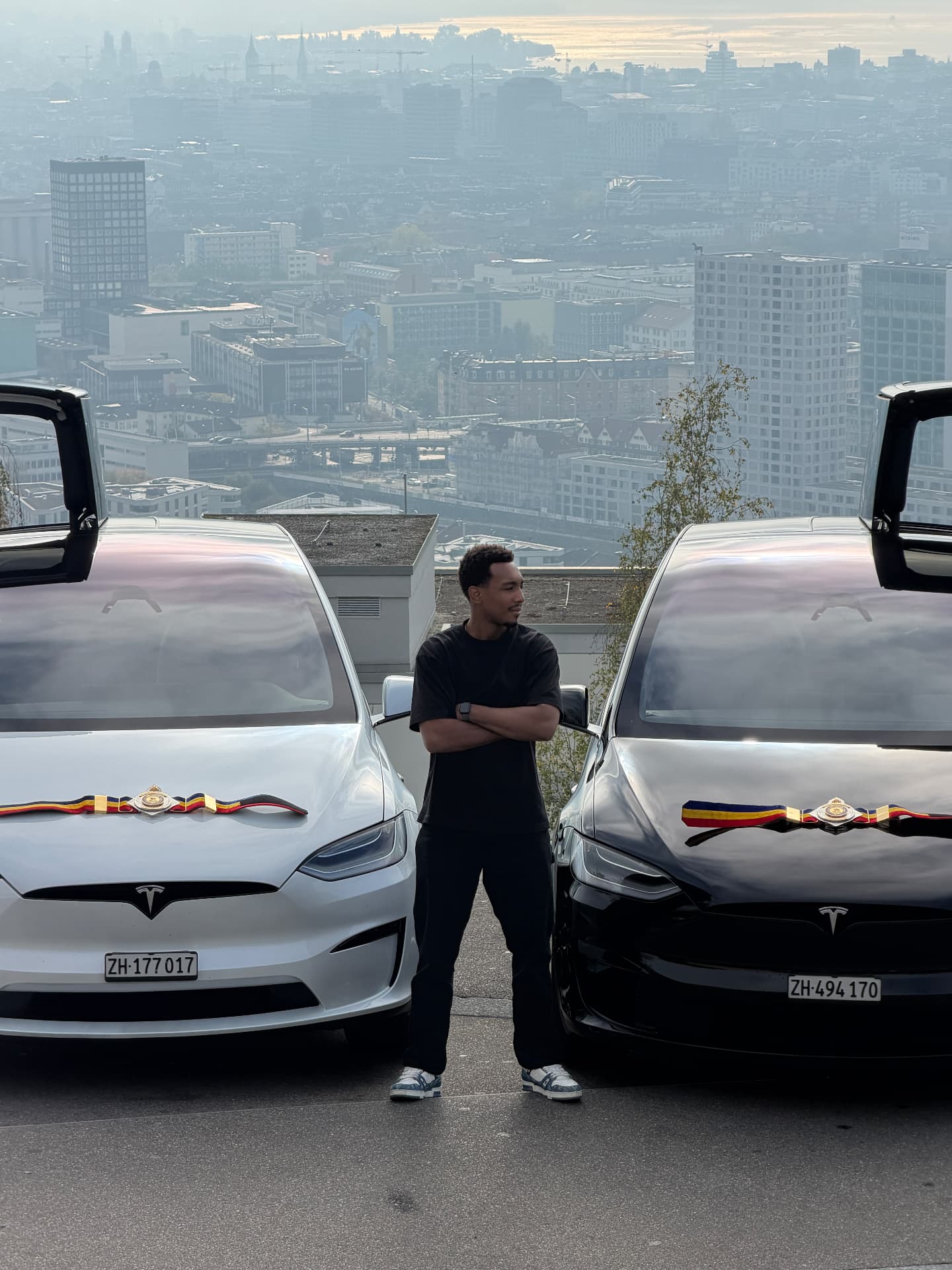Dani Rodriguez mit zwei Championship-Gürteln zwischen den Tesla Model X Tiger und Uno über Zürich