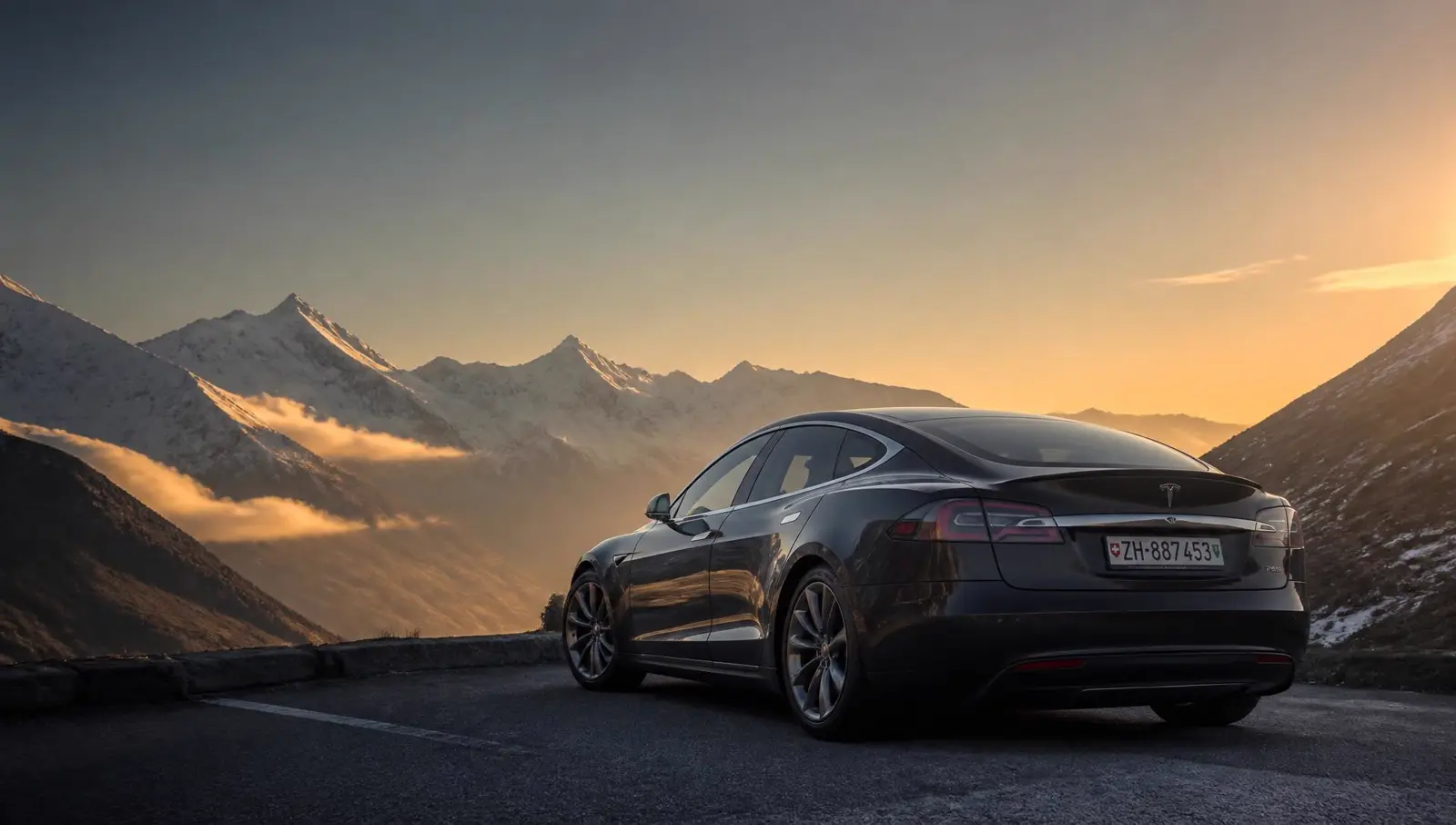 Dunkler Tesla Model S auf einer Alpenpassstrasse im Abendlicht